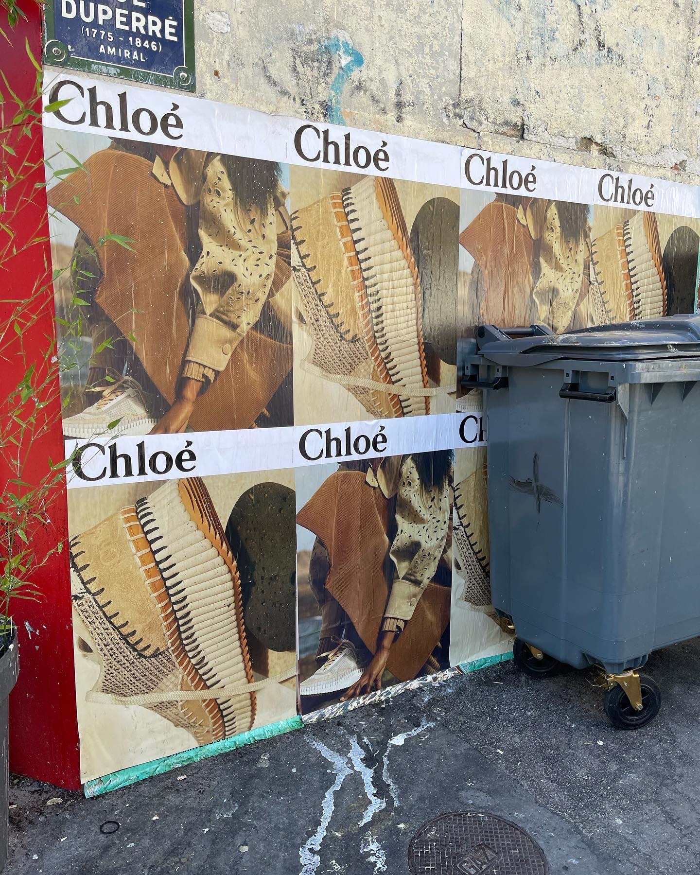 Уличная рекламная расклейка Chloé рядом с контейнерами — контраст бренда и городской реальности